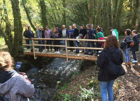 multitud personas junto a un rio en medio del monte, la mayoría están sobre un puente